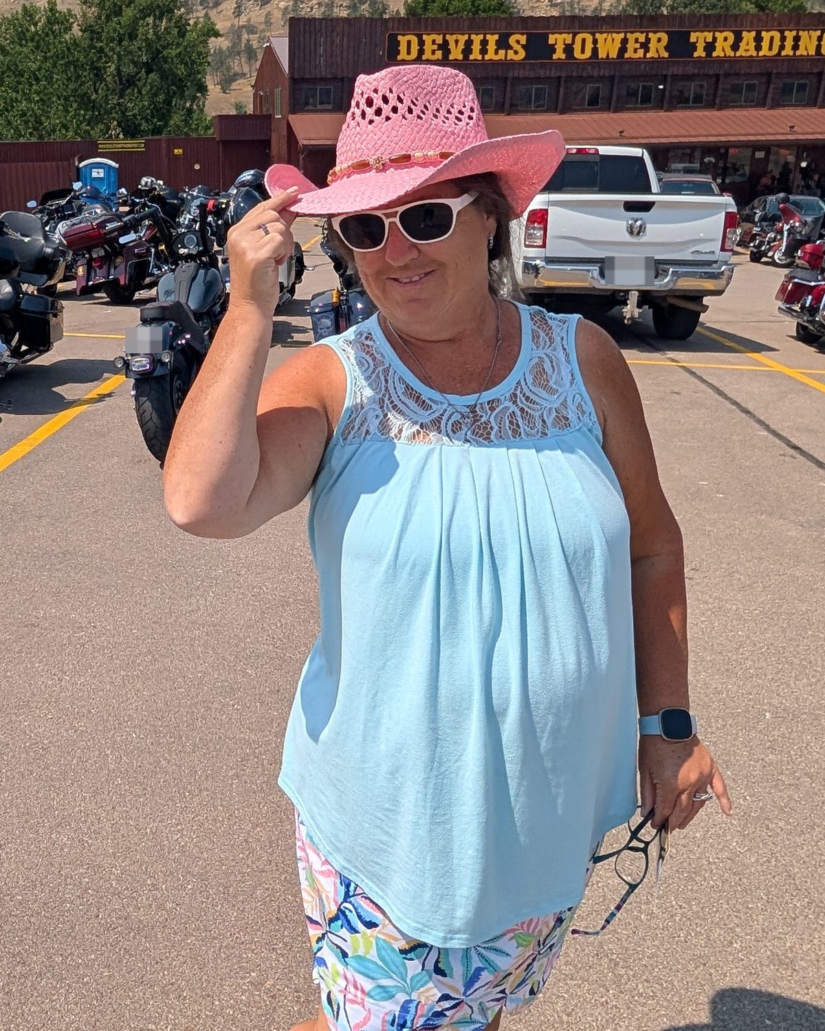 Nicole outside the Devils Tower Trading Post, tipping a pink straw cowboy hat